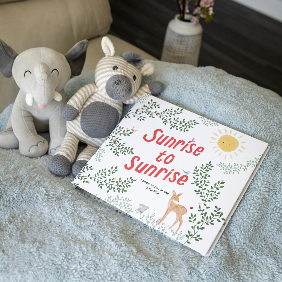 Sunrise to Sunrise NICU baby memory book displayed with stuffed animals and flowers on neutral nursery shelf
