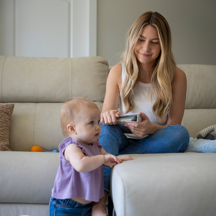 Mom holding Sunrise to Sunrise NICU memory book while toddler looks on in living room