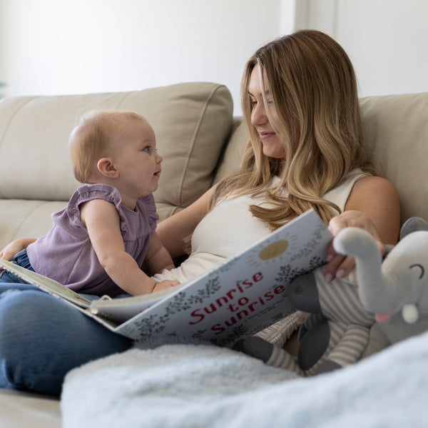 Mom and toddler reading Sunrise to Sunrise NICU memory book together on couch